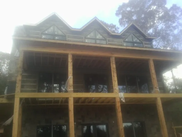 Dormers and porch framing on a large log home under construction — Roof Coating work by our crew in Glen Allen