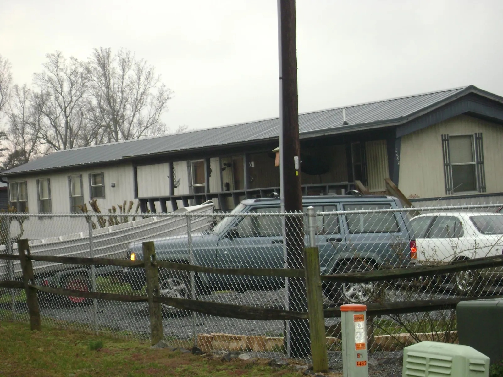 Dark metal roof on a long single story building behind a chain link fence in Glen Allen