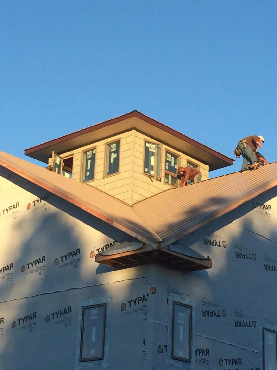 Roofers working around a rooftop cupola on a new metal roof at sunset — Roof Waterproofing in Glen Allen by Roofing Brothers
